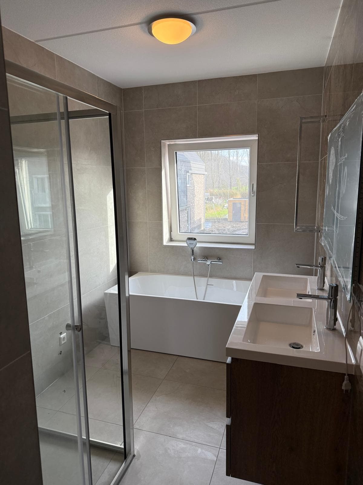Gerenoveerde badkamer met ligbad, dubbele wastafel en douchecabine