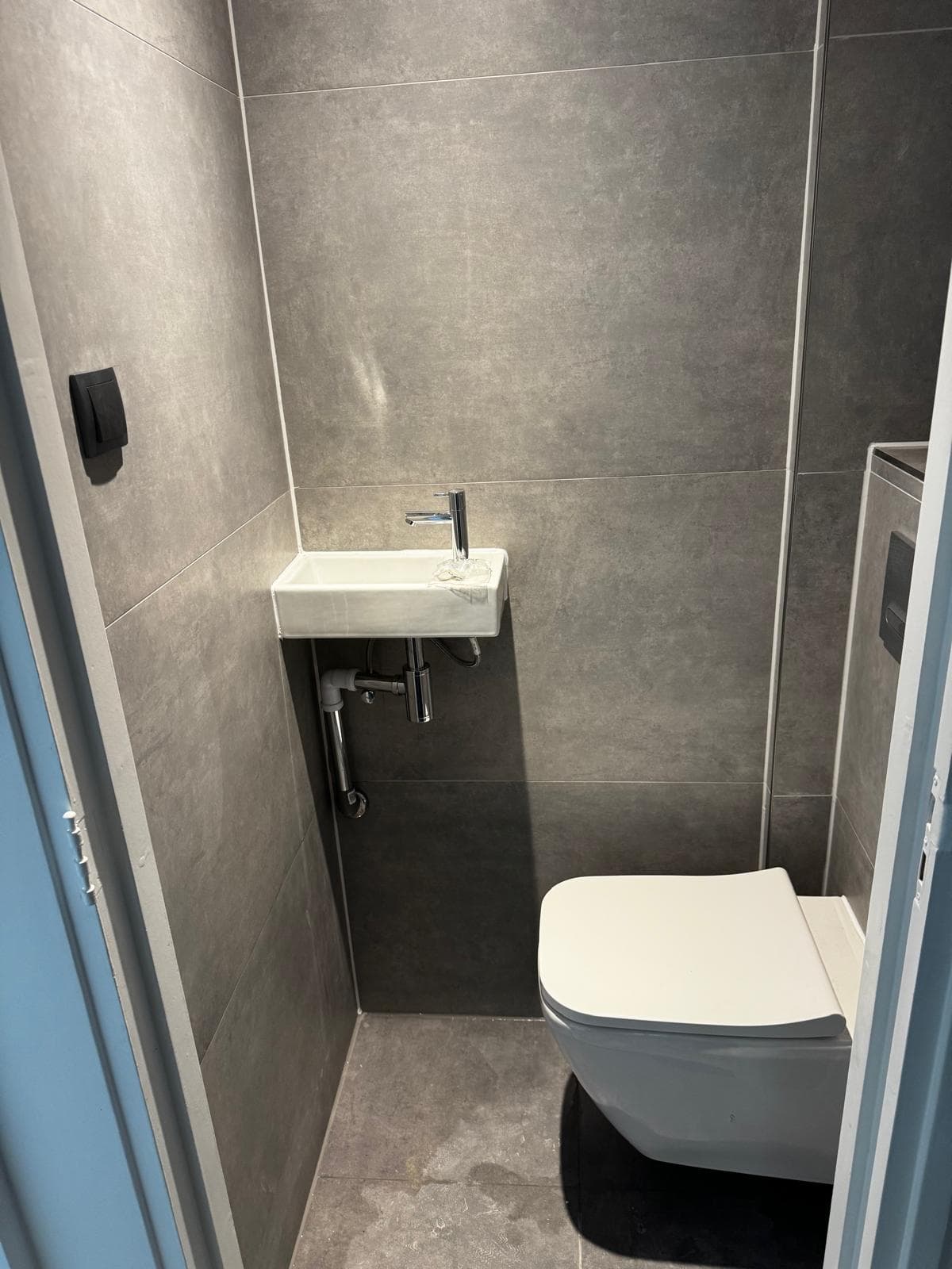 Toilet met grijze tegels, fontein en hangtoilet