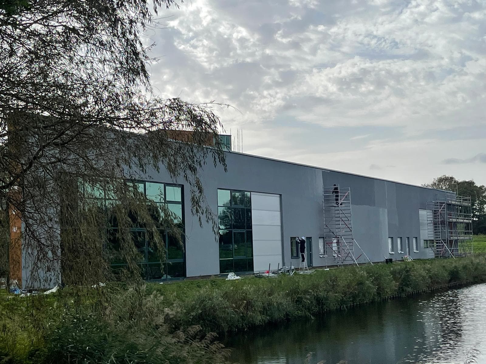 Bedrijfspand aan het water met steigers tijdens gevelwerk